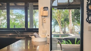 A kitchen with a large island, a built-in sink, and a view of a pool and greenery outside. - The Edge 13 Marine Parade, Newell Beach QLD 4873 (Newell)