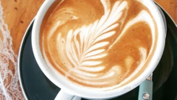Une tasse de café avec un motif en latte sur une soucoupe.