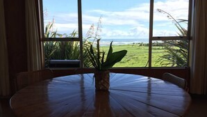 Une table ronde en bois, ornée d’une plante en pot au centre, entourée de chaises en osier.
