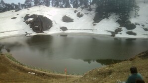 A natural landscape with a pond, snow-covered ground, and a forest in the background. - Lato The Huts River Touch Guesthouse  (Kullu)