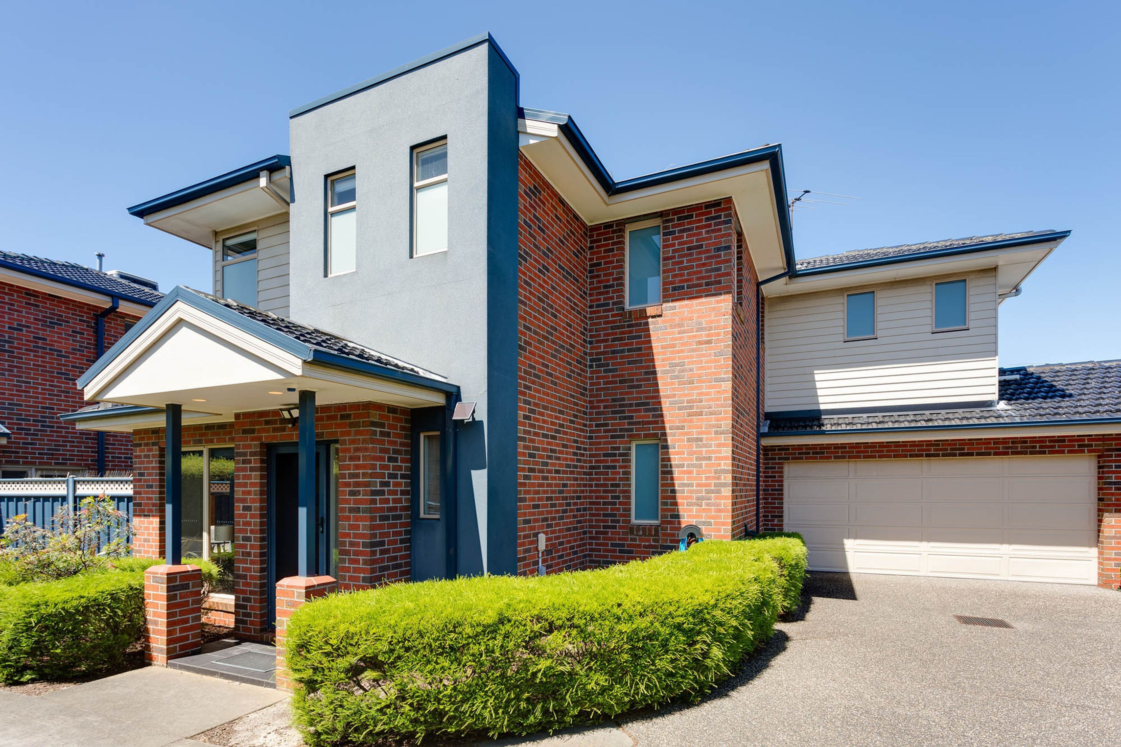 A modern two-story house with a garage, a covered entryway, and a well-maintained front yard.