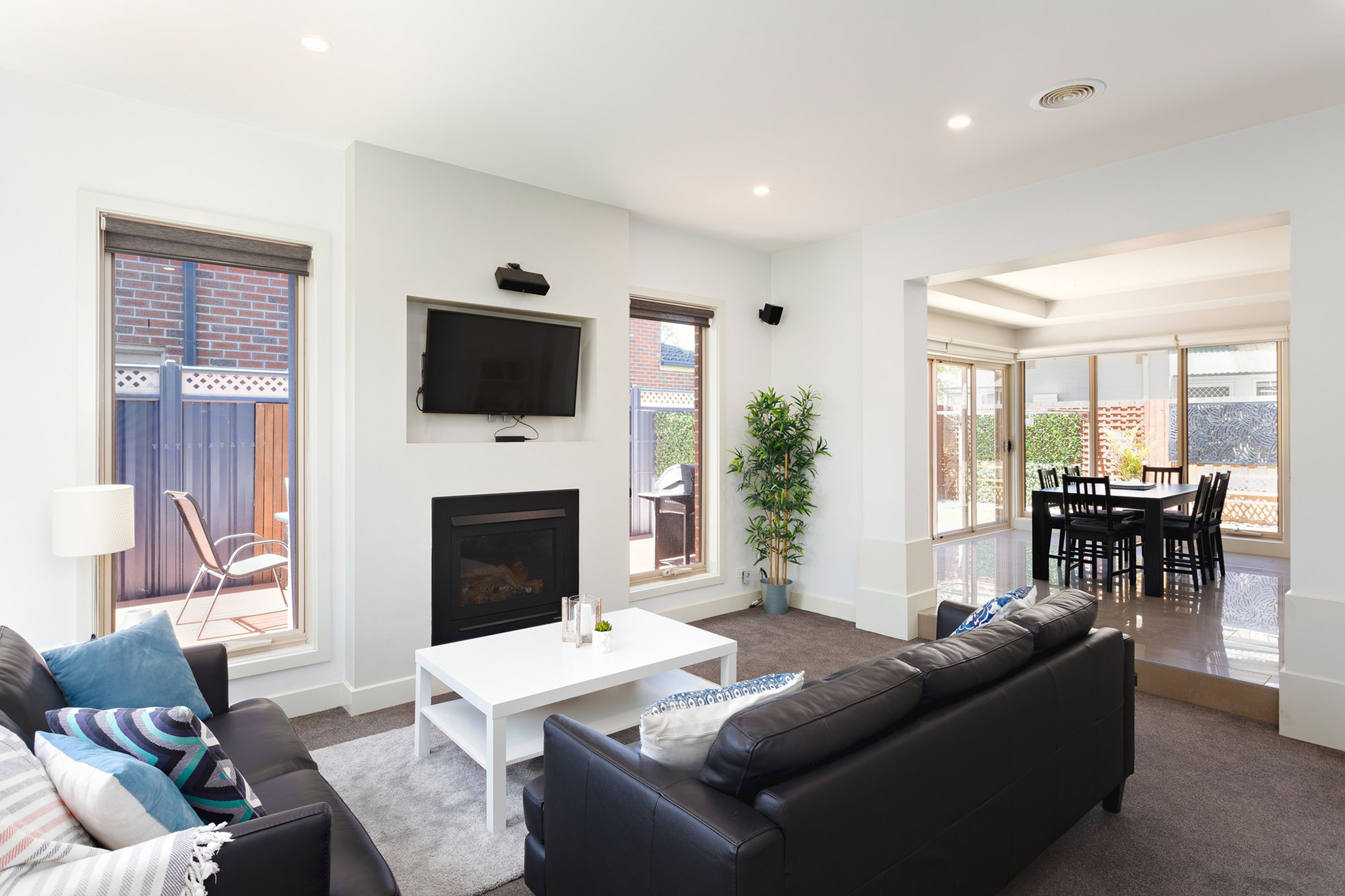 A modern living room with a fireplace, a flat-screen TV, and a dining area with a table and chairs.