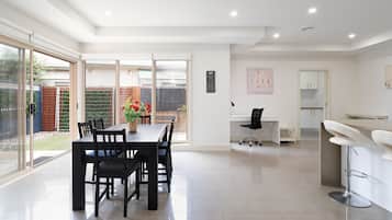 A modern kitchen with a dining area, a white countertop, and a black chair.