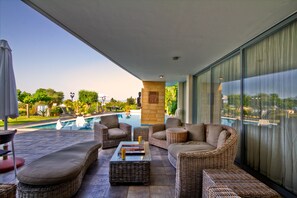 Un espacio de estar al aire libre cubierto con mobiliario de mimbre, una piscina y vistas del paisaje circundante.