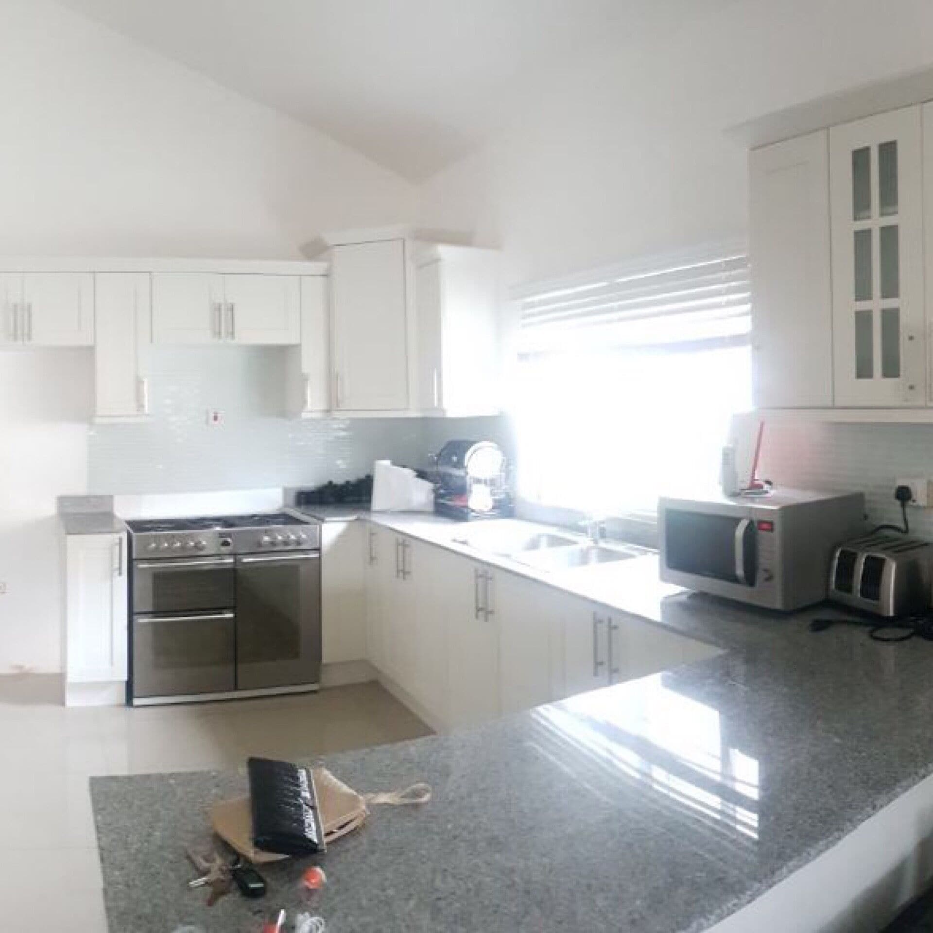 Una cocina moderna con armarios blancos, electrodomésticos de acero inoxidable y encimera de granito.