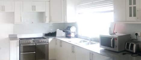 Una cocina moderna con armarios blancos, electrodomésticos de acero inoxidable y encimera de granito.