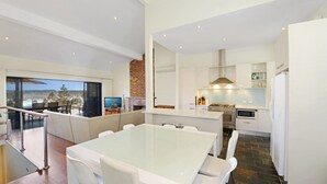Une cuisine moderne avec des meubles blancs, un grand îlot central et une vue sur l’extérieur.