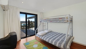 Une chambre avec des lits superposés offrant une vue sur une piscine et un paysage.