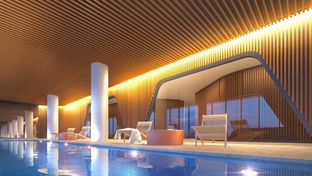 A modern indoor pool area with a clear pool, lounge chairs, and a wooden ceiling design.