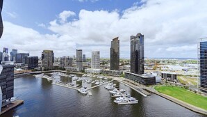 A marina with multiple boats docked, surrounded by modern high-rise buildings.