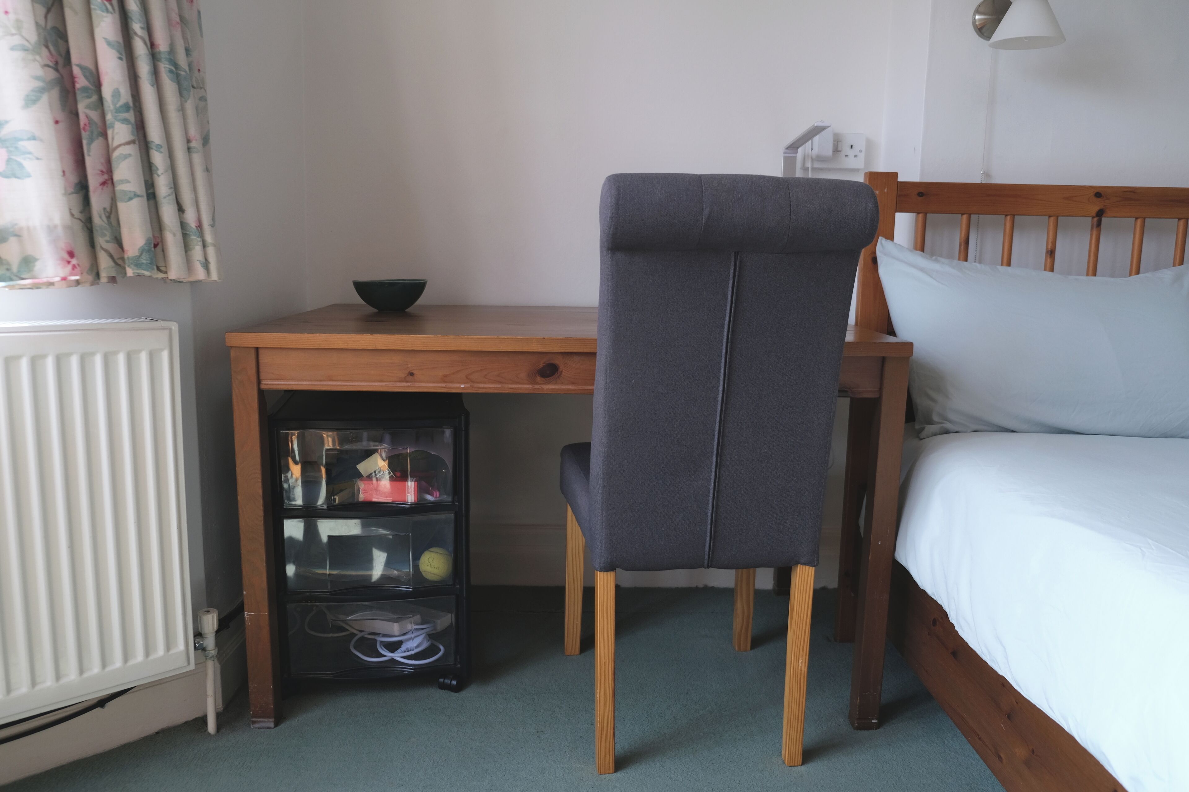 Ein Schlafzimmer mit einem hölzernen Bett, einem Schreibtisch mit Stuhl und einer Heizung.