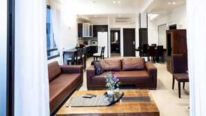 A modern living room with a brown sofa, a wooden coffee table, and a dining area in the background. - Perfect location  with panoramic sea view facing Gordon Beach (Tel Aviv-Yafo)
