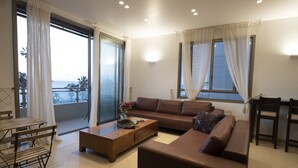 A modern living room with a brown sofa, a wooden coffee table, and a dining area with a table and chairs. - Perfect location  with panoramic sea view facing Gordon Beach (Tel Aviv-Yafo)