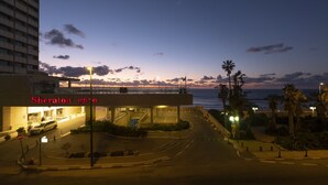 A hotel entrance with a view of the sea and palm trees at dusk. - Perfect location  with panoramic sea view facing Gordon Beach (Tel Aviv-Yafo)