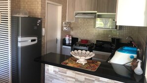 A compact kitchen with a refrigerator, stove, sink, and a microwave. - House in Buzios Geribá  (Armação dos Búzios)