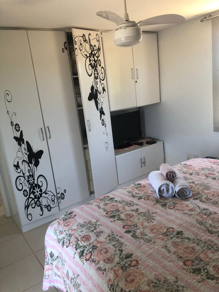 Une chambre à coucher comprenant un lit, un ventilateur de plafond, une télévision et une armoire décorée de motifs floraux.