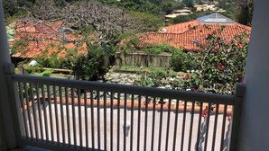 A balcony with a view of terraced houses, a garden, and the sea. - House in Buzios Geribá  (Armação dos Búzios)