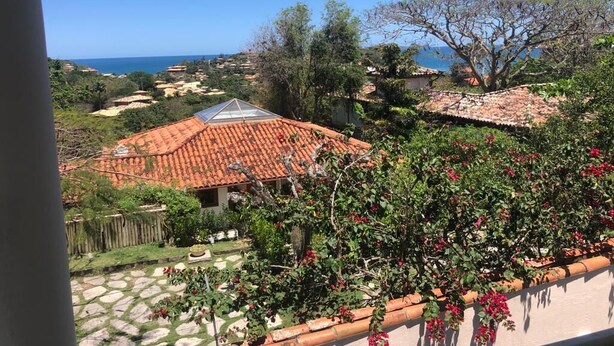 A residential area with terracotta-tiled roofs, a stone-paved courtyard, and a view of the sea. - House in Buzios Geribá  (Armação dos Búzios)