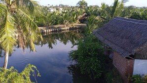 Un plan d’eau paisible, bordé de palmiers et agrémenté d’une structure au toit de chaume.