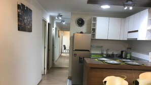 Uma cozinha moderna com armários brancos, uma geladeira e um espaço de jantar com mesa e cadeiras.