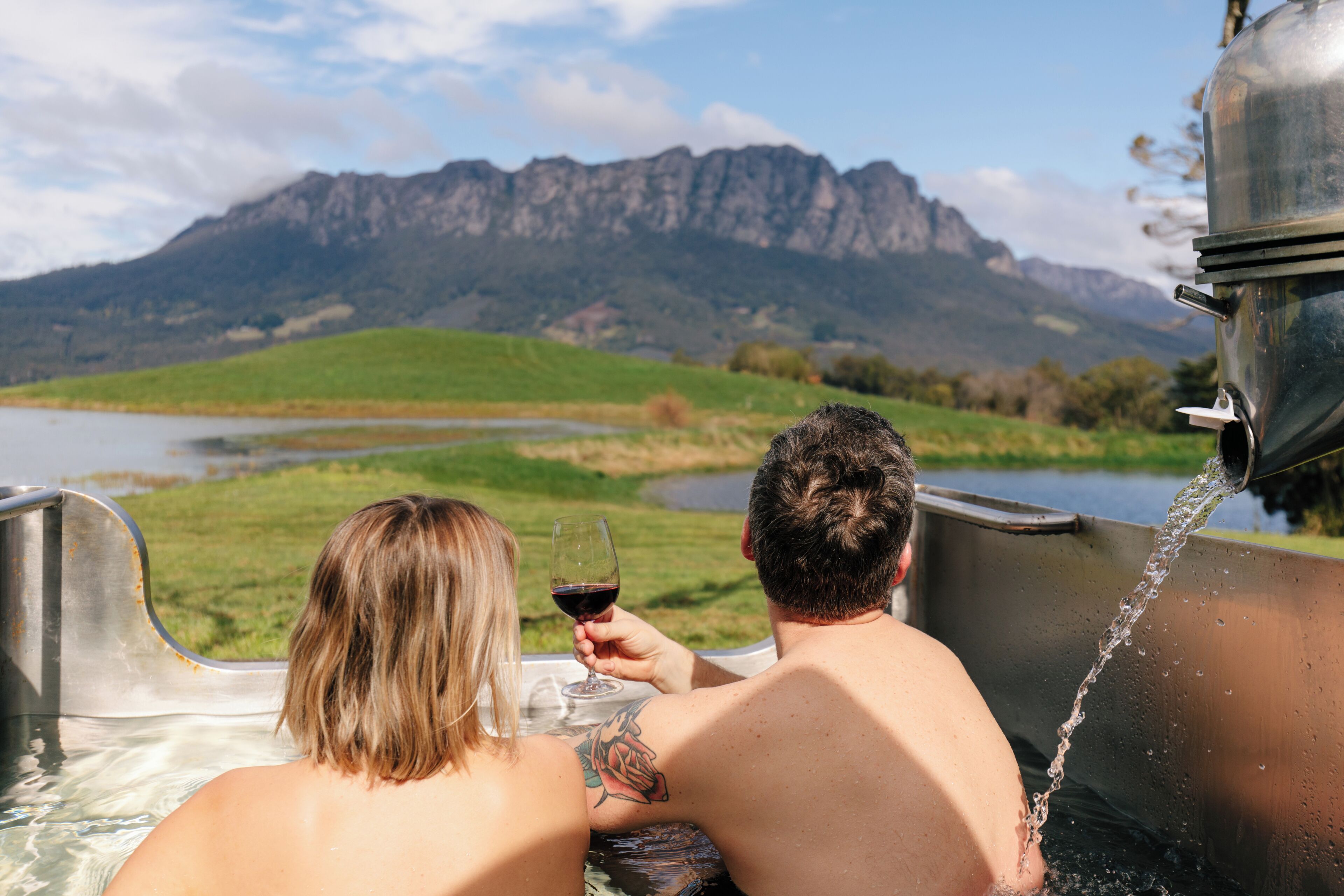 Deux personnes dans un jacuzzi avec vue sur la montagne.