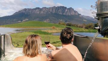 Deux personnes dans un jacuzzi avec vue sur la montagne.