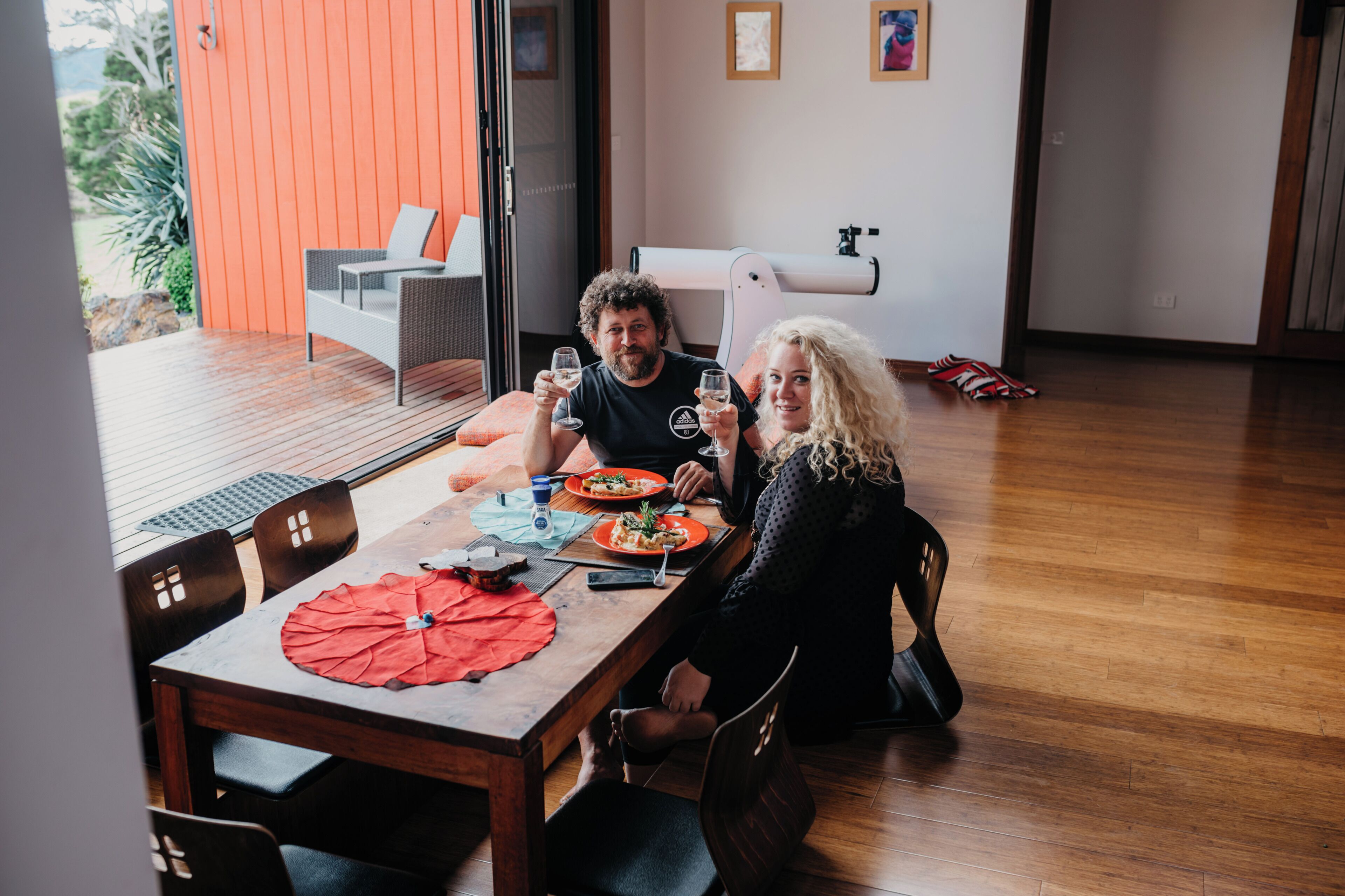 Un comedor con una mesa de madera, sillas y un paraguas rojo.