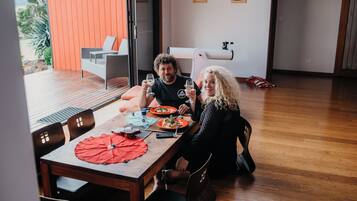 Un comedor con una mesa de madera, sillas y un paraguas rojo.