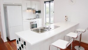 A modern kitchen with white cabinetry, a stainless steel sink, and a large window.