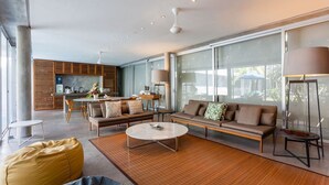 Ein modernes Wohnzimmer mit Sofa, Couchtisch und Essbereich. Im Hintergrund ist eine Küche zu sehen.