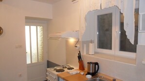 A kitchen with white cabinets, a stove, a sink, and a window with a curtain. - in a quiet position,close to sea 1 (ZADAR)