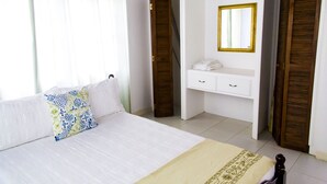 Une chambre à coucher avec un lit, une table de chevet, un miroir et une armoire.