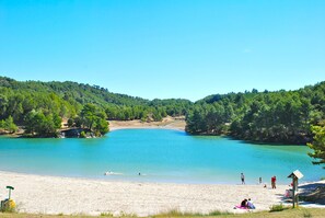Une plage bordée d’une eau turquoise et limpide, entourée de collines boisées.