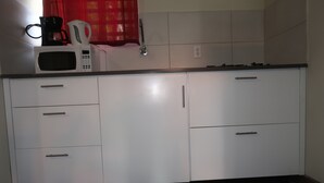 A kitchen with white cabinets, a microwave, a coffee maker, and a faucet. - Two Bedroom two bathroom Apartment A ground level (Willemstad)