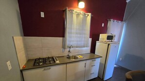 A compact kitchen with a gas stove, a sink, and a microwave. - Two Bedroom two bathroom Apartment A ground level (Willemstad)