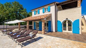 A two-story house with a patio area featuring sun loungers and a covered seating area. - Villa Leticia a perfect place for relaxed and complete vacation (Hreljići)