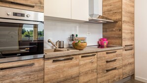 A modern kitchen with a stainless steel oven, wooden cabinets, and a built-in sink. - Villa Leticia a perfect place for relaxed and complete vacation (Hreljići)