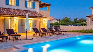 A swimming pool with lounge chairs and umbrellas, a house with a tiled roof, and a clear sky. - Villa Leticia a perfect place for relaxed and complete vacation (Hreljići)