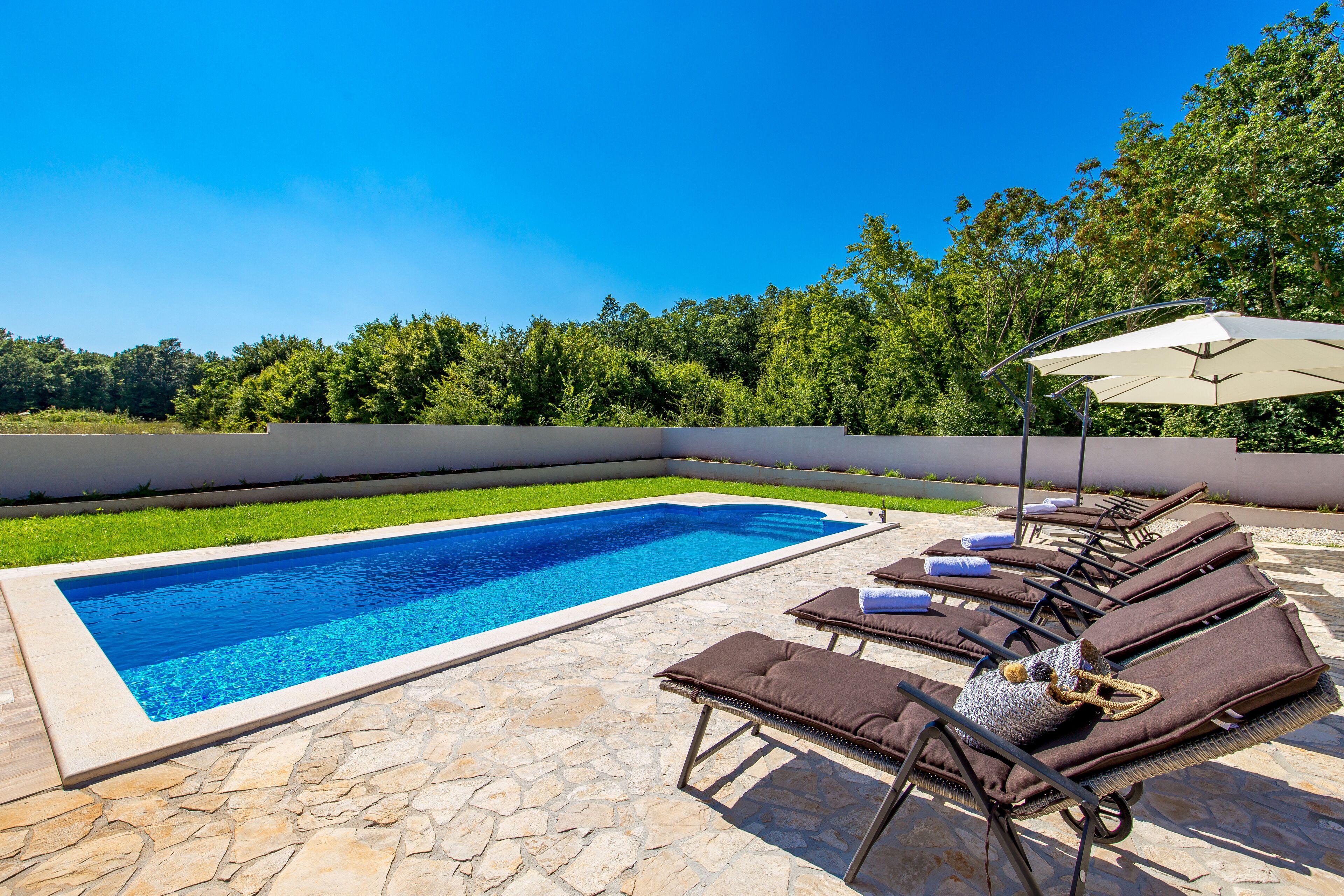 A swimming pool with lounge chairs and umbrellas.