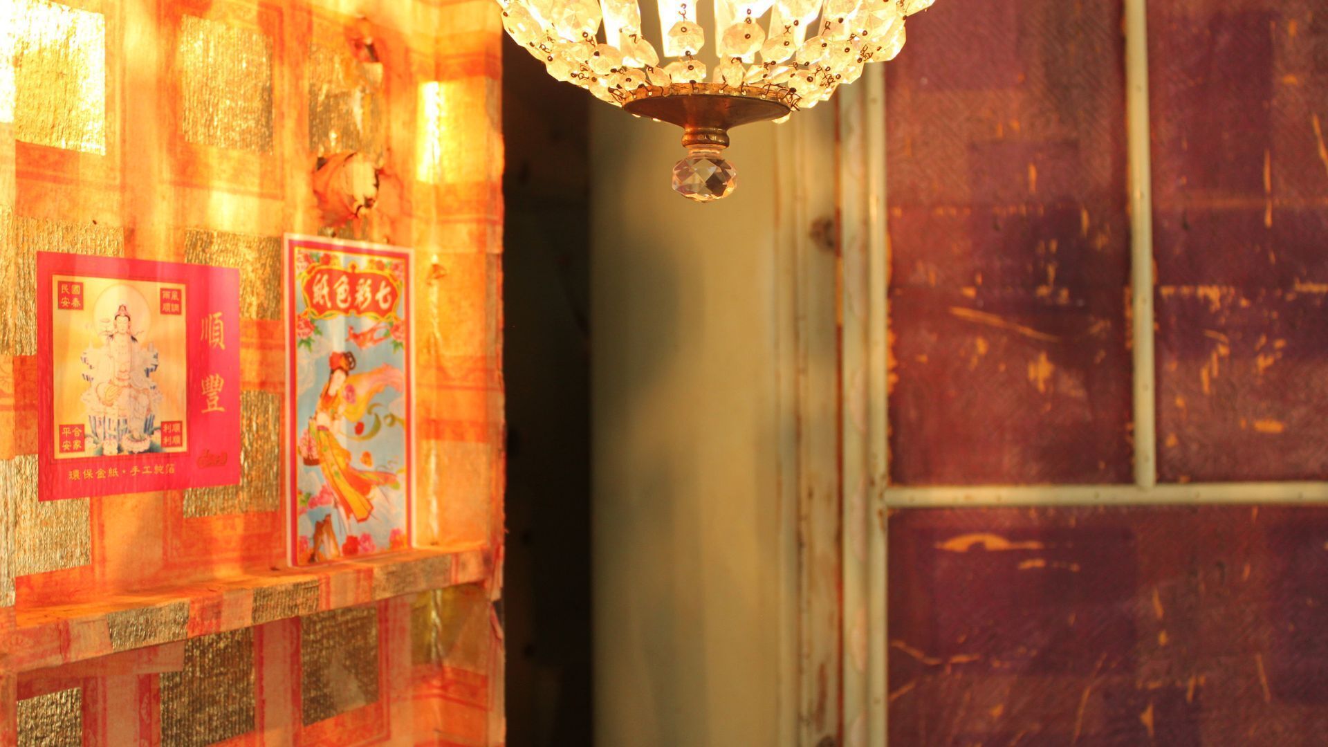 Un intérieur de style chinois traditionnel, avec un mur décoratif, un lustre suspendu et une affiche encadrée.