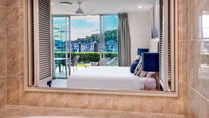 Una habitación de hotel moderna con una cama grande, un baño con bañera y un balcón con vistas a la ciudad.