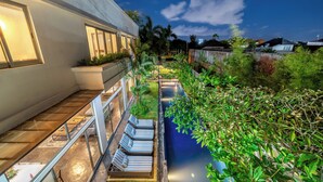 Un bâtiment moderne doté d’une piscine sur le toit, d’un espace extérieur aménagé et d’une végétation luxuriante.