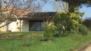 Une maison avec un toit en tuiles, un petit jardin et un chemin de terre.