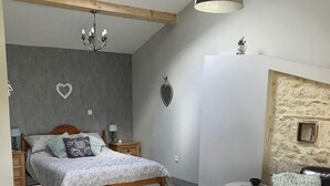 Une chambre à coucher comprenant un lit, des tables de chevet, un bureau, une chaise, un canapé, un lustre et une lucarne.