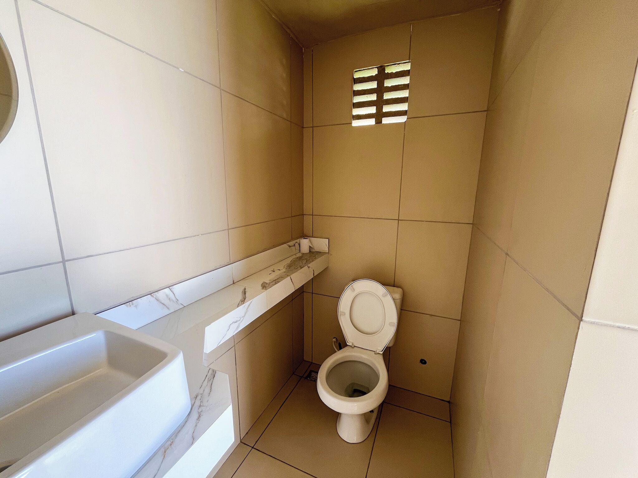 A small bathroom with a toilet, a marble sink, and a shower.