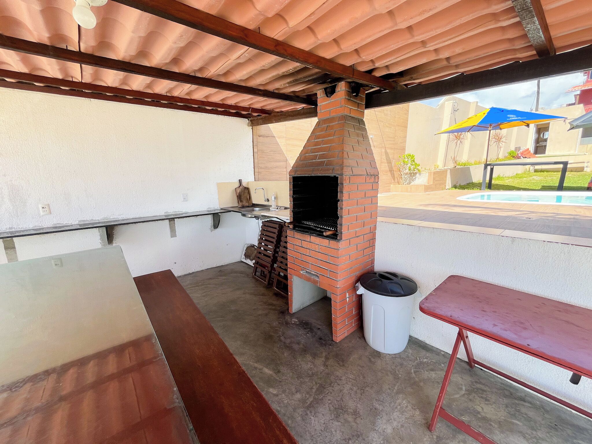 Un patio exterior con un horno de ladrillo, una mesa y un banco.