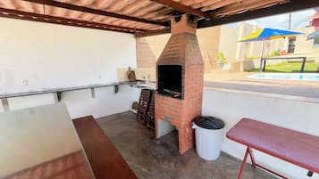 Un patio exterior con un horno de ladrillo, una mesa y un banco.