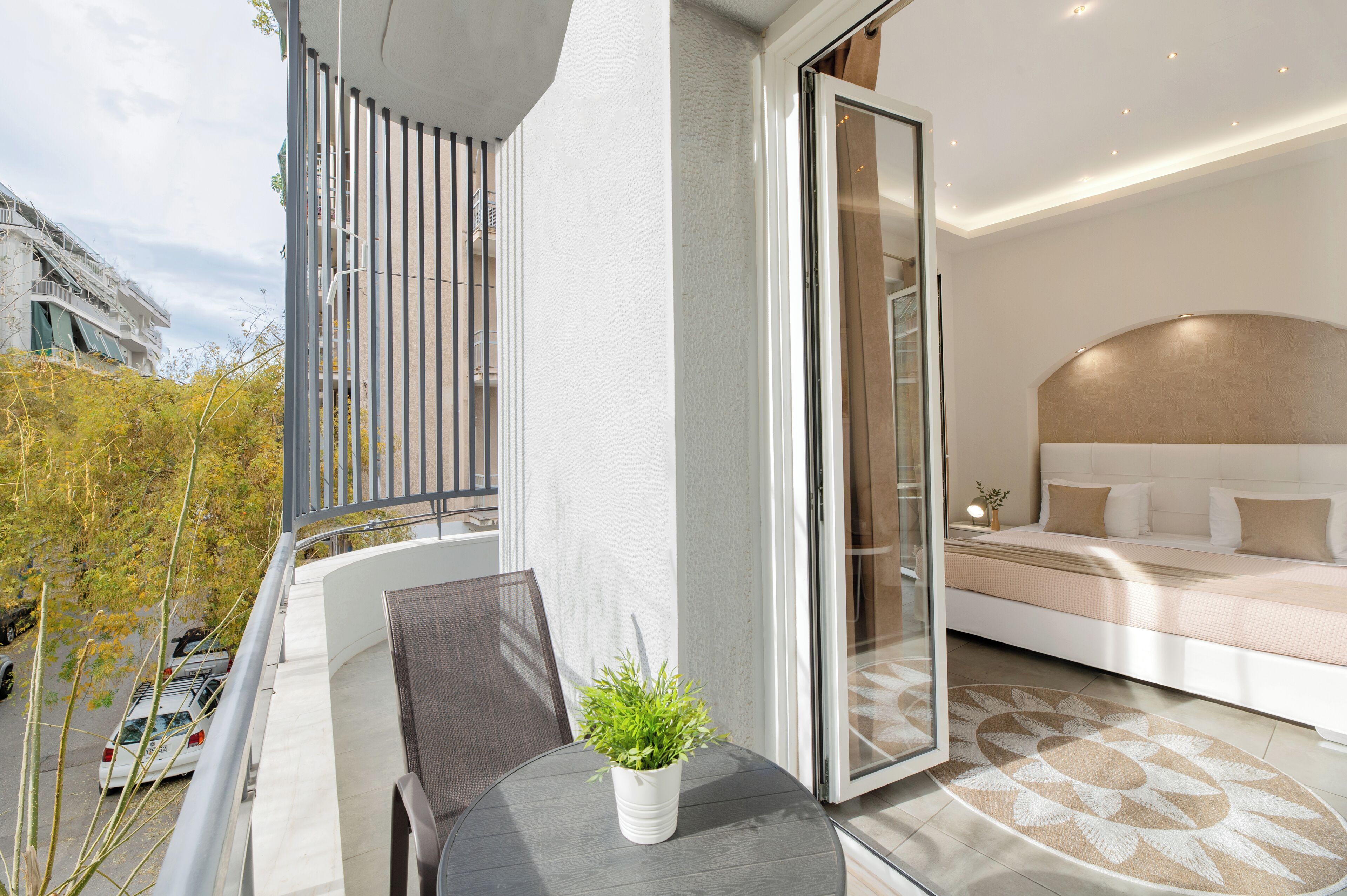Un balcon avec une table, des chaises et un pot de fleurs.