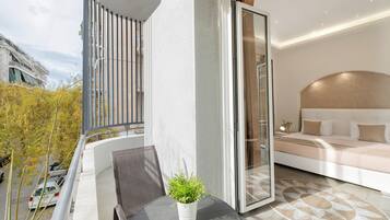 Un balcon avec une table, des chaises et un pot de fleurs.