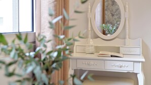 Una toeletta bianca con specchio, un libro e una bottiglia.
